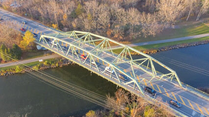Aerial view truss bridge with car traffic over Erie Canal with colorful fall foliage in late afternoon light Pittsford, New York