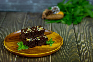 Chocolate brownies serving on wooden plate and mint leaves are bakery cakes snacks to eat with hot drinks in the morning excellent.
