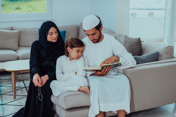 Fototapeta premium Happy Muslim family enjoying the holy month of Ramadan while praying and reading the Quran together in a modern home