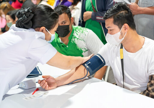 Nurse wearing a blood pressure monitor to the patient.