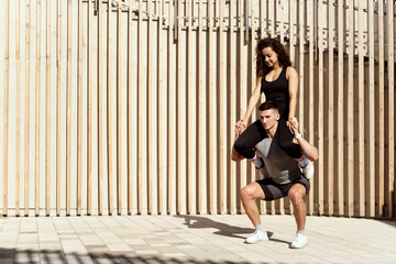 Man holding woman at the shoulders and squatting with her