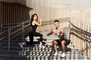 Fototapeta na wymiar Fit couple doing squats on city street stairs with focused faces