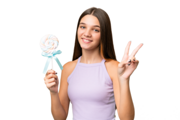 Teenager caucasian girl holding a lollipop over isolated background smiling and showing victory sign