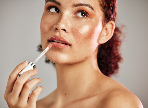 Woman, lips and lipstick application for beauty, cosmetics dermatology and skincare wellness in grey background. Female model, thinking face and lip gloss brush or makeup product for self care