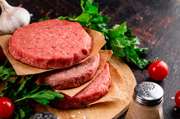 Raw burger on a wooden tray with tomatoes and dill. 