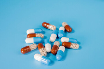 Many pills capsules on a blue background. Disease treatment concept