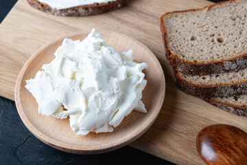 Home made rye bread on a wooden cutting board with curd cheese and ricotta