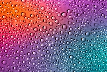 Water drops on glass as a background. Condensation on a cold drink. Multicolored background with drops texture.
