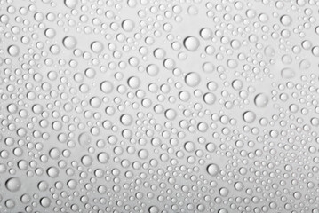 Water drops on glass as a background. Condensation on a cold drink. White background with drops texture.