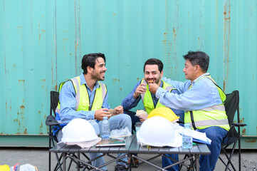 Group of logistic staff workers talk and rest sitting in the shipping yard container during break...