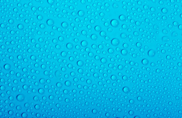 Water drops on glass as a background. Condensation on a cold drink. Blue background with drops texture.