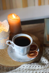 Vintage books, reading glasses, e-reader, cup of tea, bowl of biscuits and lit candle on the table. Selective focus.