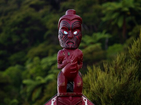 Traditional ancient red wooden Maori sculpture figure in Abel Tasman National Park Tasman South Island New Zealand