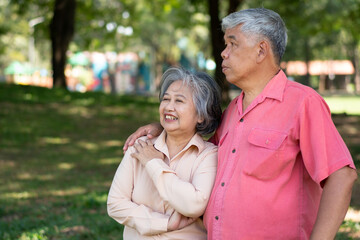 Fototapeta premium Portrait of lovely elderly couple hugging each other with love and happiness in a park outdoor. Happy smiling Elderly couple enjoying with positive emotions at garden