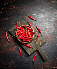 Red chili pepper pods on a cutting board. - 563930720