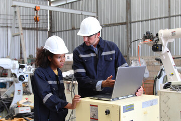 Employees using laptops to work inside an industrial factory.