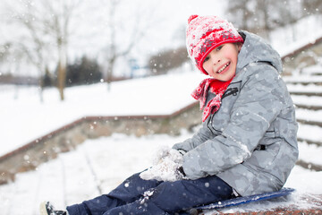 Fototapeta na wymiar Child in the winter on the street. Happy boy in winter snowy clothes outdoors