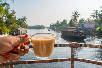 Cup of tea in backwater and houseboat background. Enjoying Tea on tropical vacation on backwater of...
