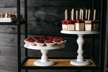Raspberry pana cotta and cupcakes on wooden stands at a party.