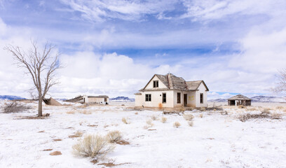 Abandoned homestead and potato bunker, San Luis Valley, Colorado, with blue sky, clouds, and snow...
