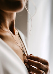Closeup of a woman with french manicure, wearing a pearl necklace.