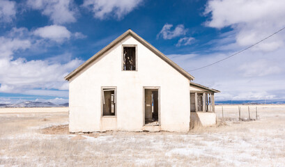 Fototapeta na wymiar Abandoned homestead on potato farm, San Luis Valley, Colorado, with blue sky, clouds, and snow on a winter day