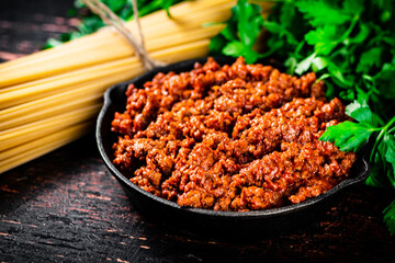 Bolognese sauce with parsley and dry pasta. 