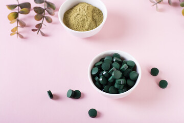 Obraz na płótnie Canvas Detox and antioxidant. Matcha powder and spirulina pills in bowls on a pink background.