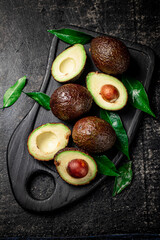 Fresh avocado with foliage on a cutting board.