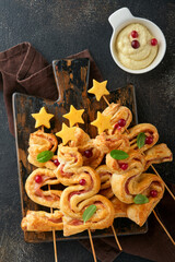 Christmas or New Year appetizer. Christmas tree shape puff pastry buns with cheese and ham. Group...