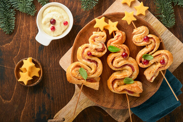 Christmas or New Year appetizer. Christmas tree shape puff pastry buns with cheese and ham. Group...