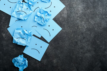 Blue crumpled sticky notes blank with drawing sad face on black background with copy space ready for your message. Blue Monday and mental health concept idea. Flat lay copy space on black background.