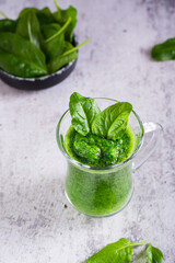 Green spinach smoothie in a glass on a gray background. Healthy food. Vertical view