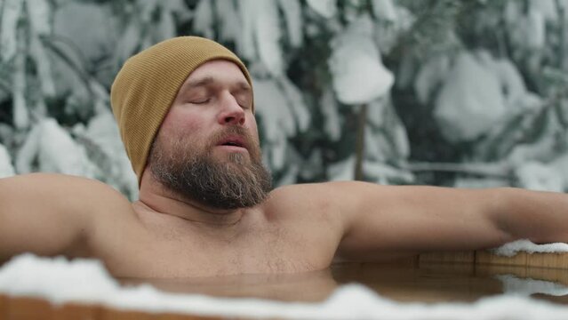 Caucasian man during the winter bath in tube outdoors. Shot with RED helium camera in 8K. 