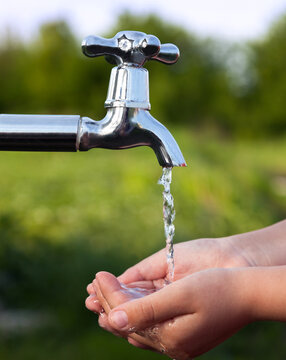child washes his hand under water the faucet in the garden