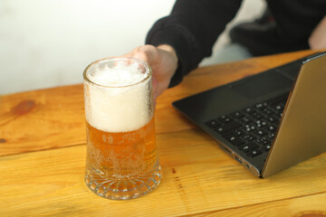 mug with beer in hand next to laptop