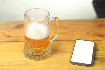 a mug with beer next to a smartphone