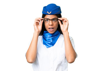 Airplane stewardess African american woman over isolated background with glasses and surprised