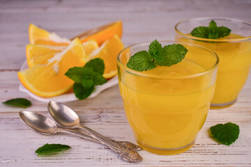 Orange cream (English citrus cream) in glasses on a white wooden background.
