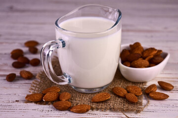 Vegan almond milk in a glass carafe on a white wooden background.
