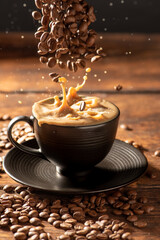 Coffee and milk, pouring coffee beans into a black cup filled with milk and coffee, dark food style photo, selective focus.