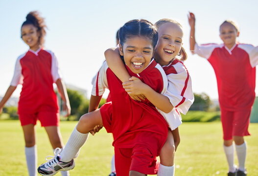 Soccer, girl celebration and field with happy piggyback, team building support and solidarity for winning game. Female kids, sports diversity and celebrate with friends, teamwork and goal in football