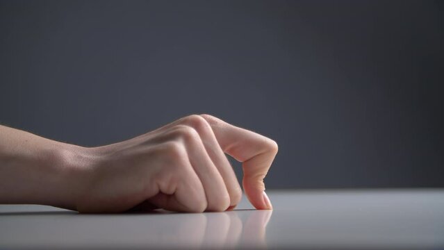 Close-up of a female hand moving along a table with a finger. Silly figures of a body as a parody of a worm. High quality 4k footage