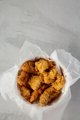 Chicken popcorn, wings, tenders in paper box on a gray background, top view. Flat lay, overhead, from above. Copy space.