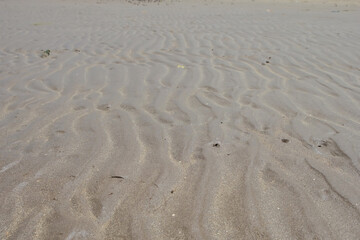 Wavy beach sand texture during daytime, summer travel background