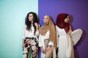Group portrait of beautiful muslim women two of them in fashionable dress with hijab isolated on colorful background representing modern islam fashion and ramadan kareem concept