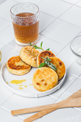 syrniki with honey on a white plate