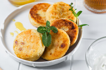 syrniki with honey on a white plate