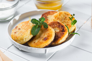 syrniki with honey on a white plate