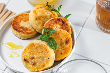 syrniki with honey on a white plate